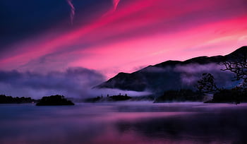 A captivating misty sunrise over a serene lake with pink skies and silhouettes of hills. HD wallpaper
