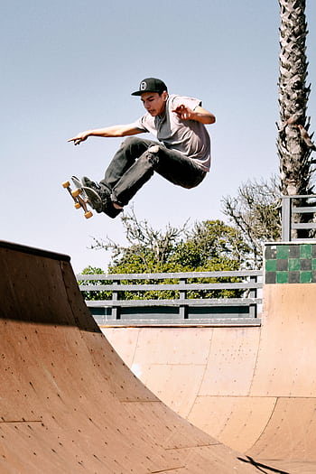 A teenage skateboarder performing a high-flying trick at an outdoor skate park in Cayucos, California. HD phone wallpaper