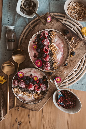 Top view of nutritious smoothie bowls with berries, chia seeds, and oats on a wooden table. HD phone wallpaper