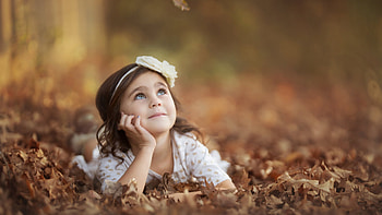 Cute Little Girl Is Lying Down On Dry Leaves Wearing White Dress Looking Up In Blur Background Cute HD wallpaper