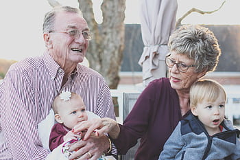 Grandparents spending joyful moments with their grandchildren in an outdoor setting, captured candidly. HD wallpaper