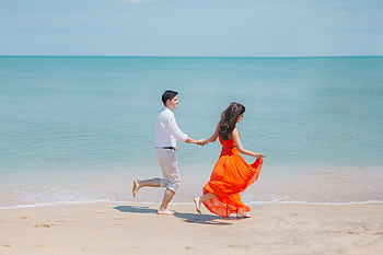 A joyful couple runs barefoot along Baku's sunny coastline, embodying care summer love. HD wallpaper