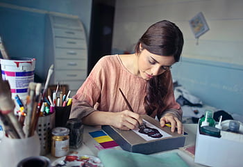 Female artist deeply engaged in painting at her creative studio workspace. HD wallpaper