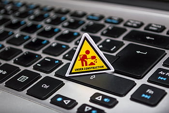 A miniature under construction sign placed on a laptop keyboard symbolizing digital development. HD wallpaper