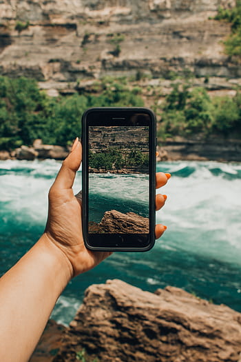 Hand holding smart capturing the stunning view of Niagara Falls rapids. HD phone wallpaper