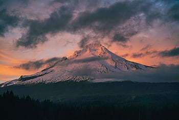 Captivating view of snow-capped Mount Hood surrounded by vibrant sunset skies and dramatic clouds. HD wallpaper