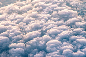 Captivating aerial view of fluffy clouds against a tranquil blue sky, offering a serene natural scene. HD wallpaper