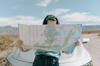 A woman holds a map while traveling through the scenic desert of California, USA. HD wallpaper