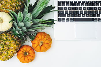 A top view of pineapples, pumpkins, and a laptop on a clean white background. HD wallpaper