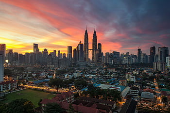 Breathtaking view of Kuala Lumpur skyline with Petronas Towers at sunset, showcasing vibrant urban architecture. HD wallpaper