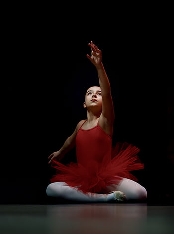 Ballerina in red tutu elegantly poses under spotlight, highlighting graceful movement. HD phone wallpaper