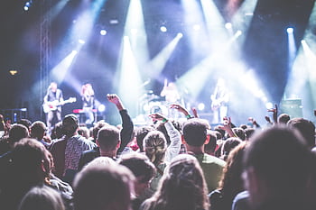 Energetic concert scene with a vibrant audience and band performing under bright lights. HD wallpaper