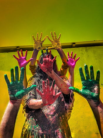 Group of people celebrating Holi with colorful painted hands and vibrant background. HD phone wallpaper