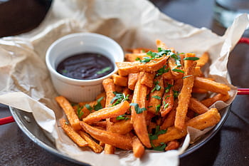 Close-up of crispy sweet potato fries garnished with parsley served with a dip. HD wallpaper