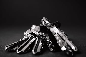 A close-up shot of a pile of metallic keys on a dark surface, emphasizing security and precision. HD wallpaper