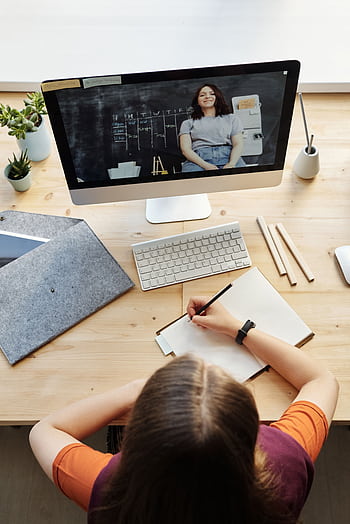 A teenage student attentively participates in a virtual classroom setting from a home office workspace. HD phone wallpaper