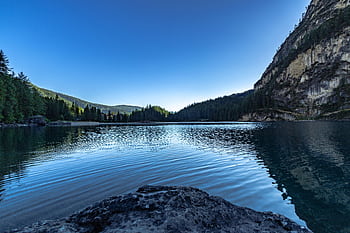 Serene mountain lake with clear reflections of trees and a blue sky. HD wallpaper