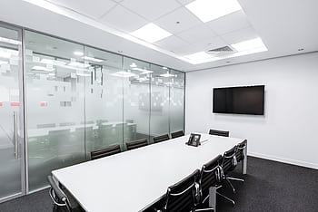 Sleek, minimalist conference room with glass walls, long table, and office chairs. HD wallpaper