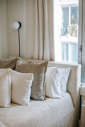 A serene and cozy bedroom setup featuring soft linen cushions and natural light. HD phone wallpaper