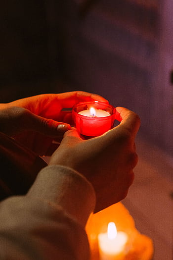 Hands holding a red votive candle flame, symbolizing hope, prayer, and spirituality. HD phone wallpaper