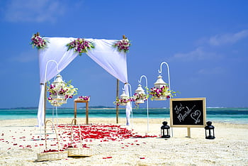 Stunning beach wedding arrangement with floral decor and lanterns on a sunny day. HD wallpaper