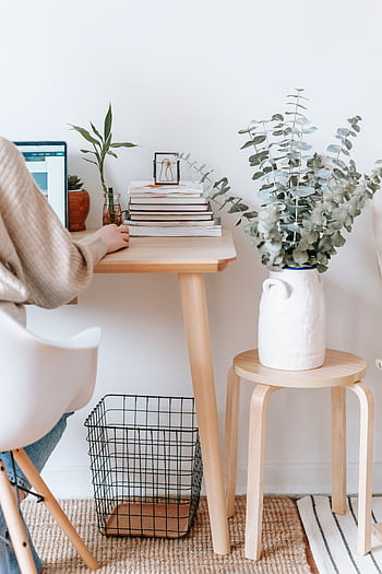 Cozy workspace with a laptop, books, and plants, promoting a relaxed, creative atmosphere. HD phone wallpaper