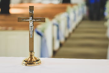 A gold crucifix on an altar with blurred church pews in the background. HD wallpaper