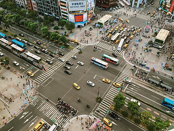Aerial view showcasing busy city street life with traffic and pedestrians at an intersection. HD wallpaper