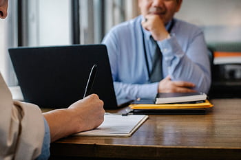 Close-up of a job interview interaction with documents and a laptop in an office. HD wallpaper
