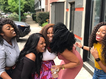 A joyful group of friends sharing a moment of laughter on a sunny day outdoors. HD wallpaper