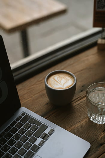 A cozy café scene with a laptop and latte on a wooden table by the window. HD phone wallpaper