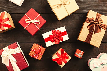 Top view of various wrapped gifts with bows on a wooden table, perfect for Christmas or celebrations. HD wallpaper