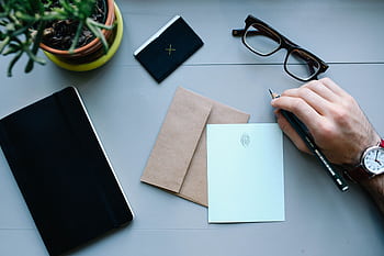 Overhead view of a desk with writing tools, glasses, envelope, and notebooks, showcasing office work essentials. HD wallpaper