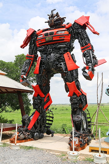 A towering robot sculpture made from recycled materials stands outdoors on a clear day. HD phone wallpaper