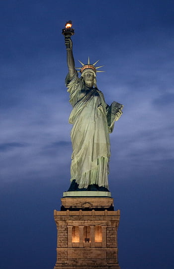 The Statue of Liberty illuminated against a dusky evening sky in New York City. HD phone wallpaper