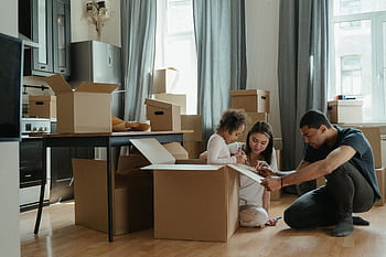 A family unpacks moving boxes in their new home kitchen, creating a cozy atmosphere. HD wallpaper