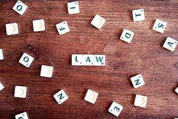 Scrabble tiles spelling 'LAW' on a wooden table, symbolizing connections to education and legality. HD wallpaper