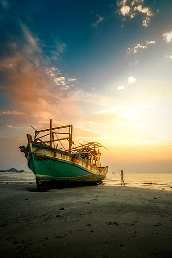 Stunning view of an abandoned fishing boat at sunset on a Thai beach, capturing tranquil beauty and wanderlust. HD phone wallpaper