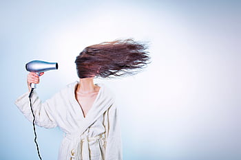 Woman in a bathrobe using a hairdryer, hair flying wildly. Indoor setting. HD wallpaper