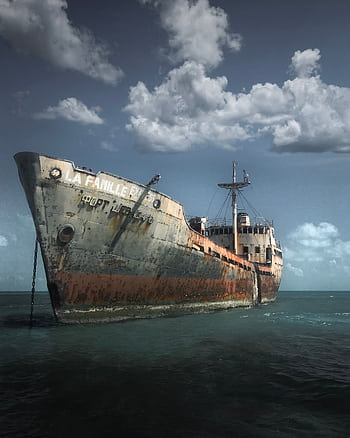 A rusty abandoned ship partially submerged in the ocean under a cloudy sky, evoking nostalgia. HD phone wallpaper