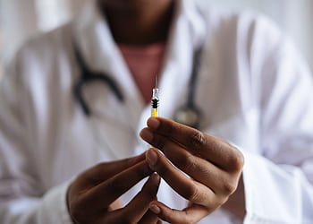 Close-up of a healthcare professional holding a syringe, symbolizing medical care and vaccination. HD wallpaper