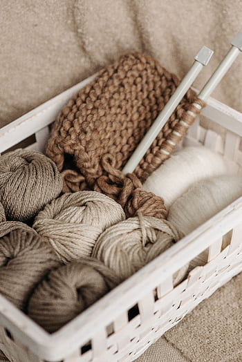 A rustic basket filled with wool yarn and knitting needles, ideal for crafts and hobbies. HD phone wallpaper
