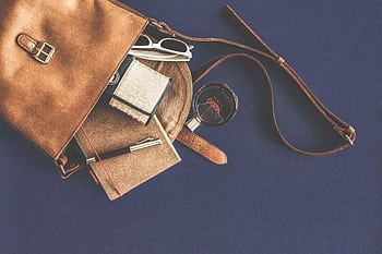 Stylish flat lay of a leather handbag with luxury accessories including sunglasses, wallet, notebook, and pen. HD wallpaper