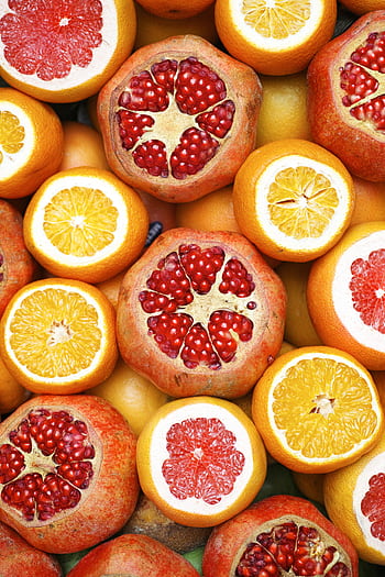 Colorful mix of sliced citrus fruits and pomegranates showcasing freshness. HD phone wallpaper
