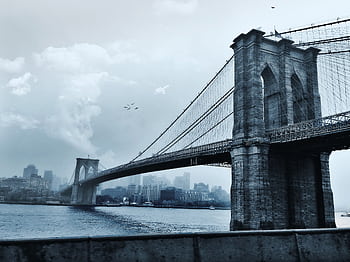 Scenic view of the iconic Brooklyn Bridge against a cloudy New York City skyline. HD wallpaper