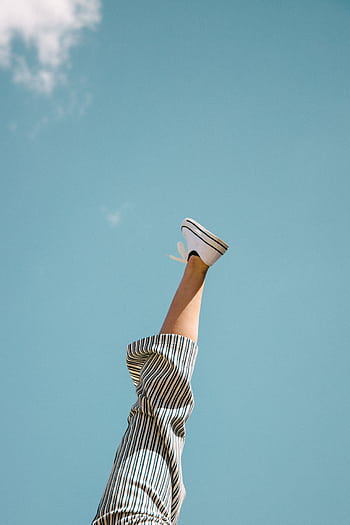 A single leg playfully sticks upward with striped pants against a bright blue sky background. HD phone wallpaper
