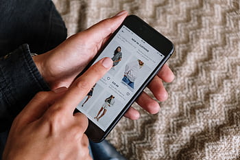 Person browsing clothing items on a smart, showcasing modern online shopping experience. HD wallpaper