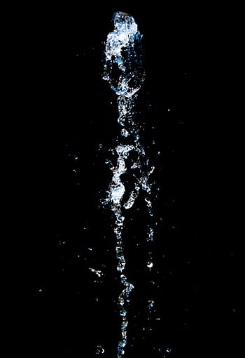 High-speed capture of a dynamic water splash against a plain black background, showcasing fluid motion. HD phone wallpaper