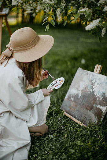 Young woman painting in a lush garden, capturing nature's beauty in spring. HD phone wallpaper