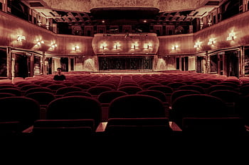 An elegant vintage theater with plush velvet seats and warm lighting, perfect for a serene cinematic experience. HD wallpaper